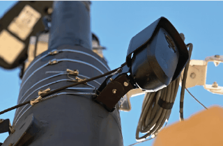 Close up of street camera on light pole against blue sky