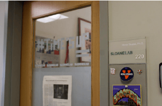 Classroom door with glass window and Sloane Lab sign next to door
